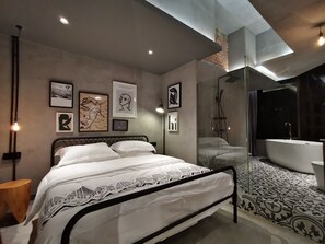 A modern bedroom with a large bed, a glass-enclosed shower, and artwork on the walls.