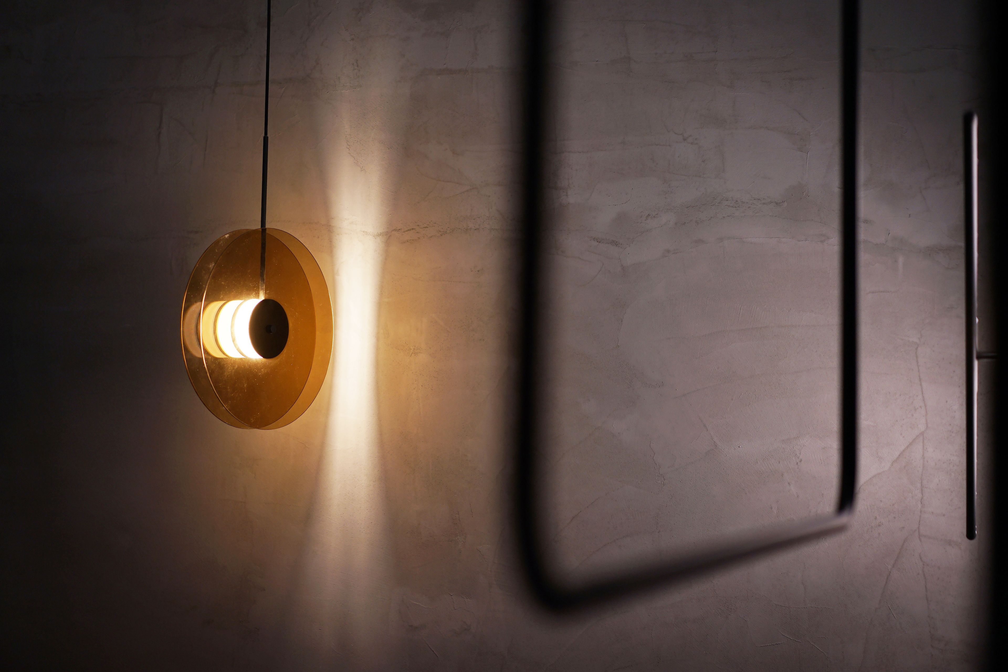 A modern interior with a textured wall and a hanging light fixture.