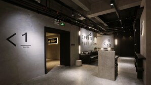 Een modern interieur met een bordje met daarop 'ROOM 1' en een receptie met een digitaal welkomstbord.