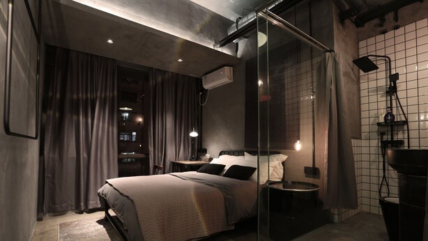 Een moderne slaapkamer met een douchecabine van glas, een bed met hoofdeinde en een nachtkastje.