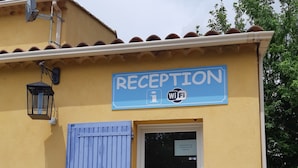 A reception area with a blue door, a sign indicating WiFi availability, and a no-smoking sign. - Camping Les Sources (Courthezon)