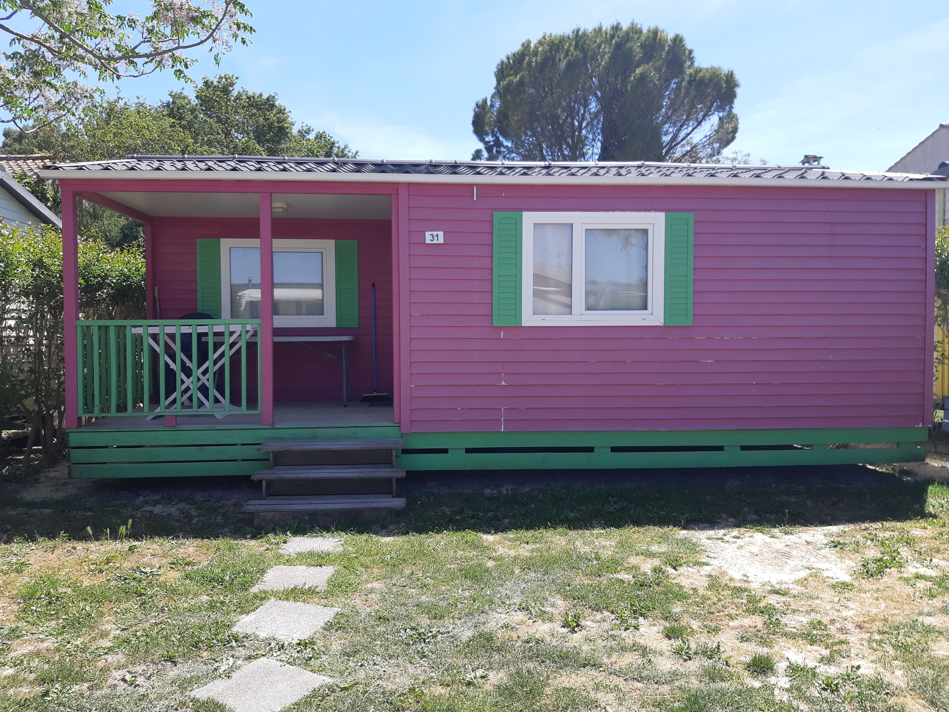 Une petite maison à un seul étage, dotée d’un porche, portant le numéro 31 et dont la porte est peinte en vert.