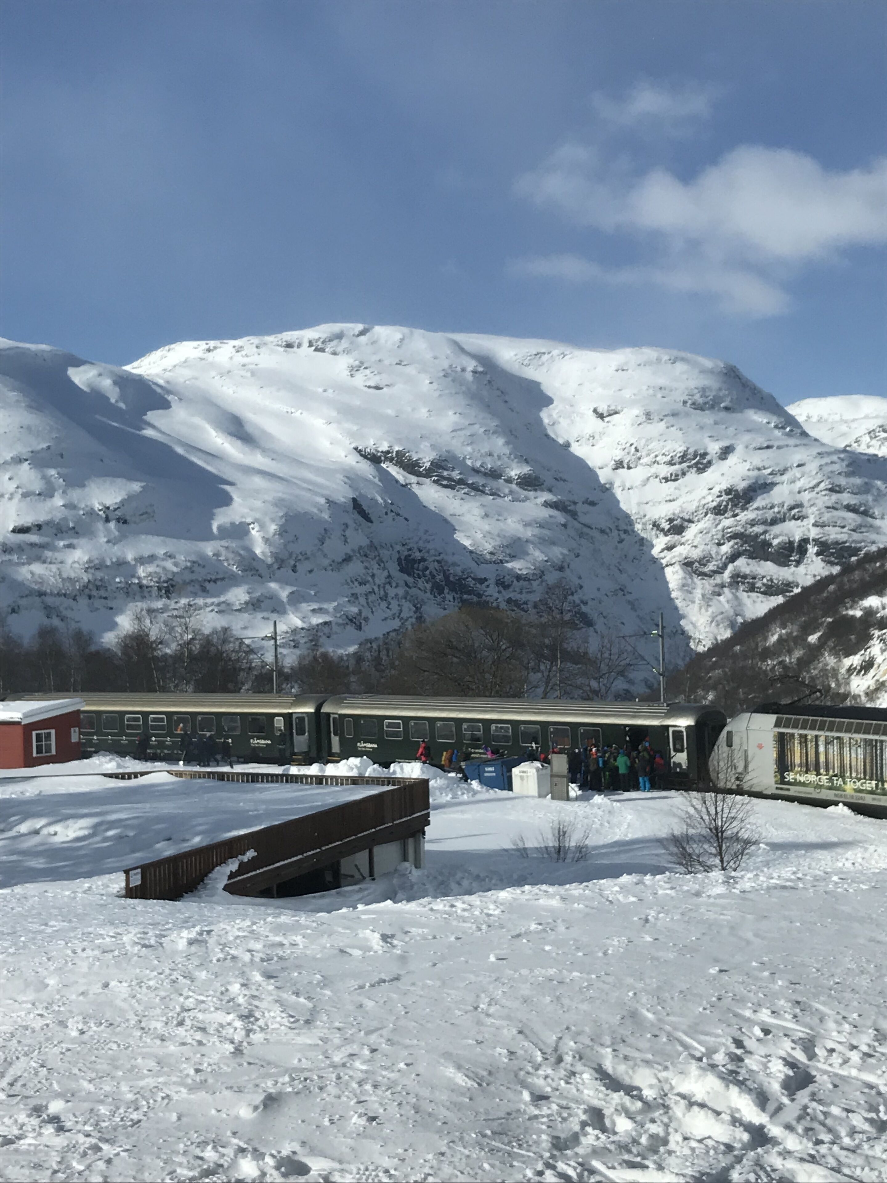 Una estación de tren cubierta de nieve con montañas al fondo.