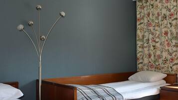 Een slaapkamer met twee houten bedden, een nachtkastje en een hoge vloerlamp.