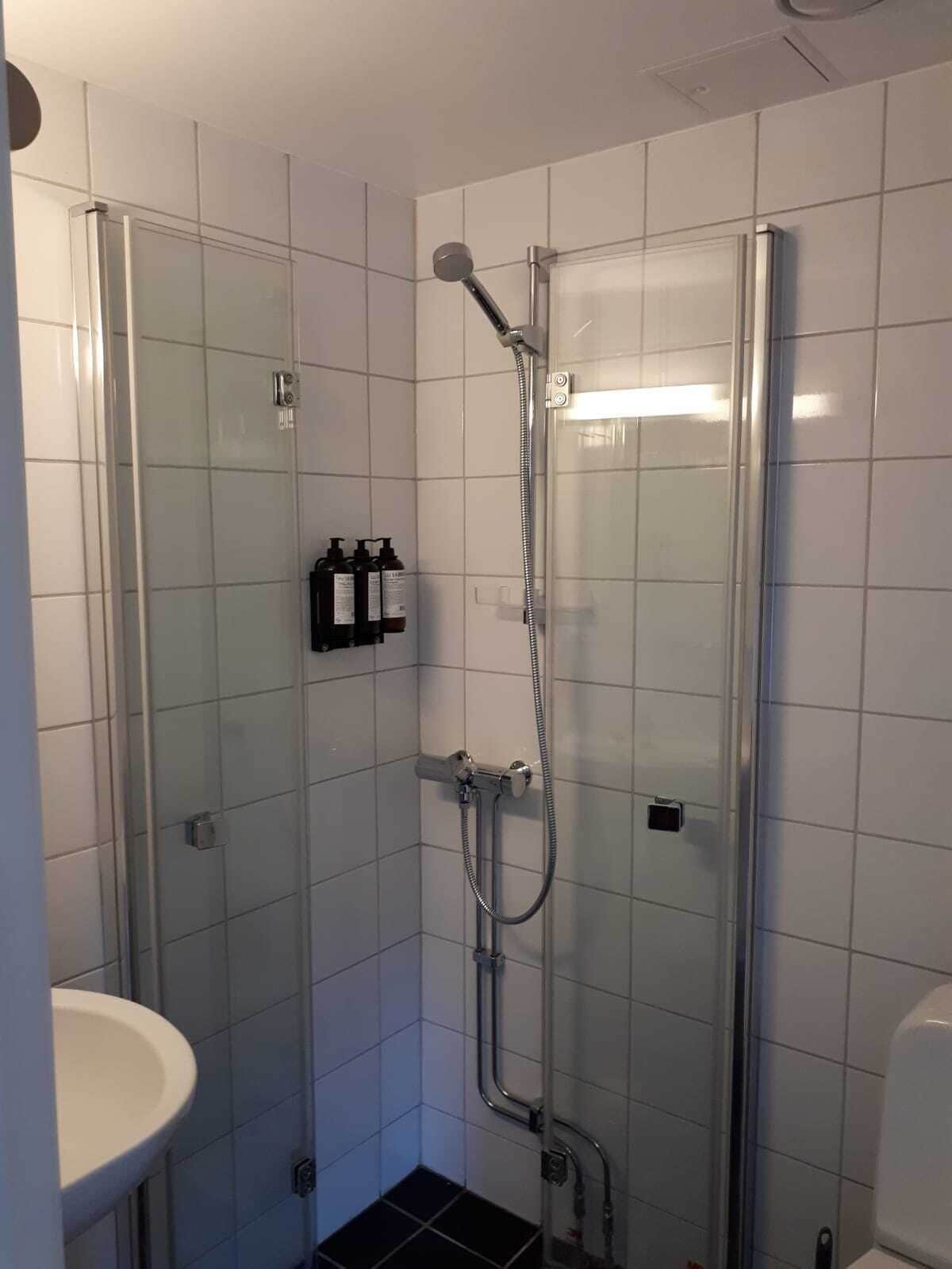 Un baño pequeño y moderno con cabina de ducha de vidrio, un lavabo blanco y un inodoro.