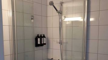 Un baño pequeño y moderno con cabina de ducha de vidrio, un lavabo blanco y un inodoro.