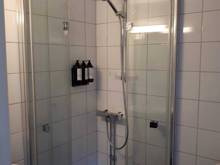 Un baño pequeño y moderno con cabina de ducha de vidrio, un lavabo blanco y un inodoro.