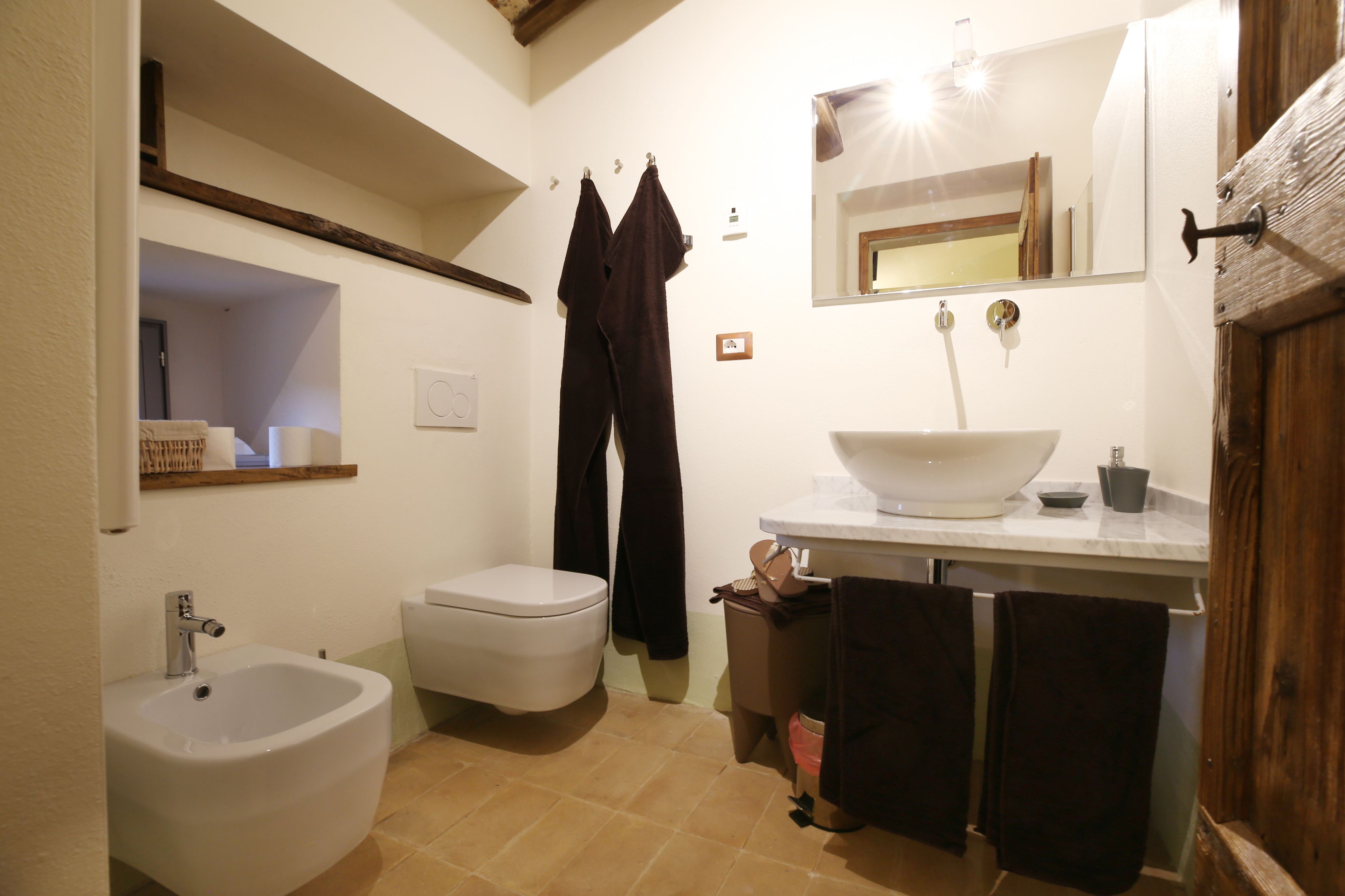 A bathroom with a bidet, toilet, sink, and mirror.