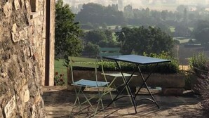 A stone building with a table and chairs outside, overlooking a valley with mist and distant hills. - Casa Minotti (Gubbio)