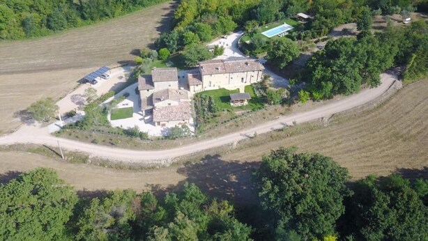 An aerial view of a large estate with multiple buildings, surrounded by fields and dense trees. - Casa Minotti (Gubbio)