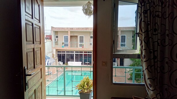 Balcón abierto con vistas a una piscina y edificios cercanos.