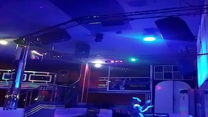 Una habitación tenuemente iluminada con una escalera, una zona de bar y un letrero de neón.