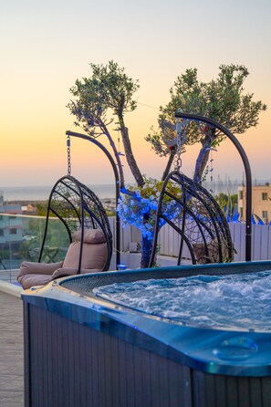 A hot tub with a hanging chair and a tree in the background.