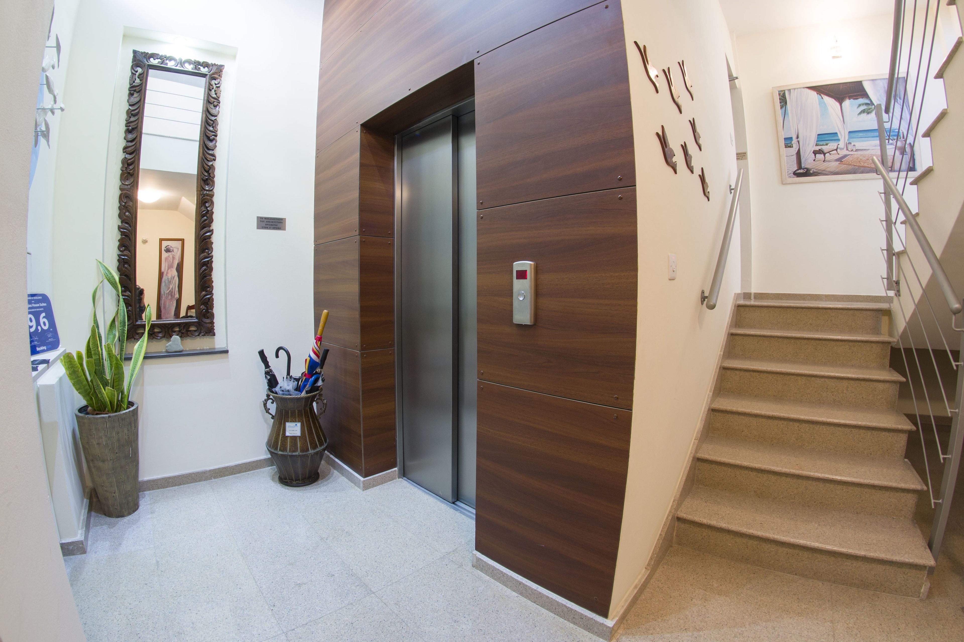 A hallway with a wooden wall, an elevator, a staircase, and a potted plant.