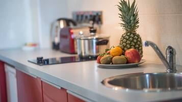 A kitchen counter with a plate of fruits, a pineapple, and a coffee maker.