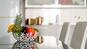 Een fruitschaal op een tafel in een moderne keuken met witte kasten en een keukeneiland.