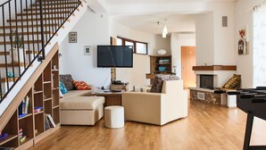 A spacious living room with a wooden staircase, a flat-screen TV, a foosball table, and a fireplace. - Arton Villa in the Heart of Istria (Zminj)