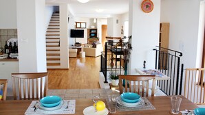 A dining area with a wooden table set for four, a kitchen in the background, and a staircase leading to another level. - Arton Villa in the Heart of Istria (Zminj)