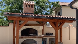 An outdoor brick oven barbecue area with a wooden pergola overhead. - Arton Villa in the Heart of Istria (Zminj)
