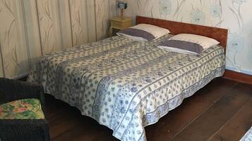 A bedroom with a bed, a nightstand, a chair, and a framed picture on the wall.