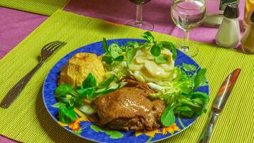 Un plato con un guiso de carne, puré de papas y vegetales sobre un mantel colorido.