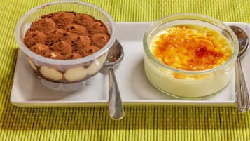 Two dessert dishes on a white plate with a spoon, placed on a green textured tablecloth.