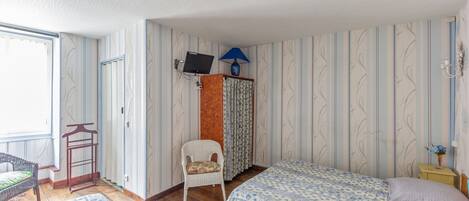 Un dormitorio con dos camas, una silla, una mesita, un televisor y una ventana.