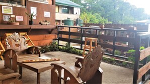 Un área de estar al aire libre con mobiliario de madera y una cerca de metal.