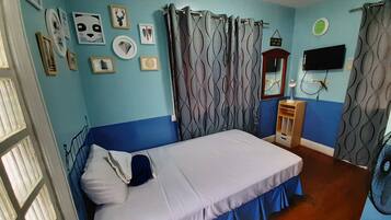 A bedroom with a bed, curtains, a mirror, a television, and wall decorations.