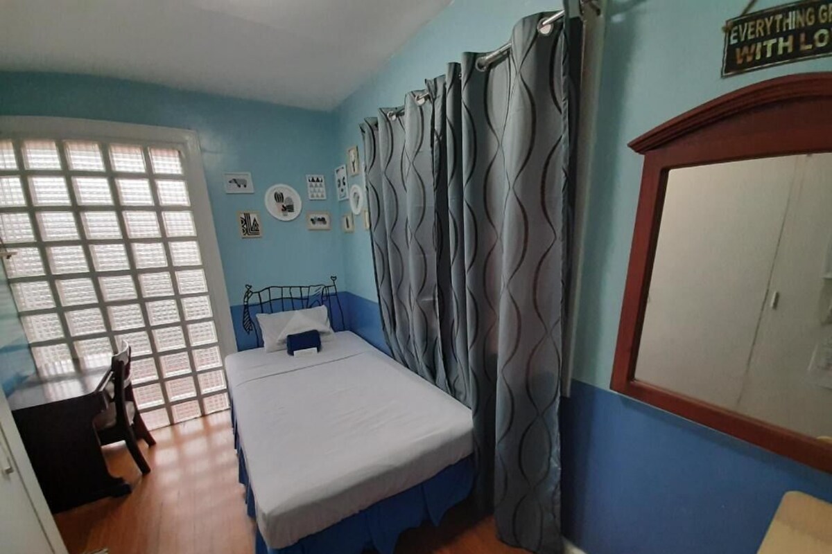 Une chambre à coucher avec un lit, des rideaux, un bureau et une fenêtre.