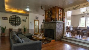 Una sala de estar acogedora con chimenea, un sofá y un comedor con sillas.