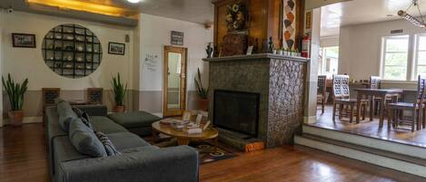 A cozy living room with a fireplace, a sofa, and a dining area with chairs.