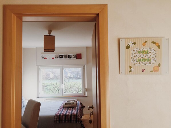 A bedroom with a bed, a chair, a window, and a wall decoration.