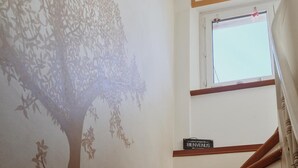 Una escala amb un mural d'un arbre a la paret i un rètol que diu "BIENVENUS" a dalt.