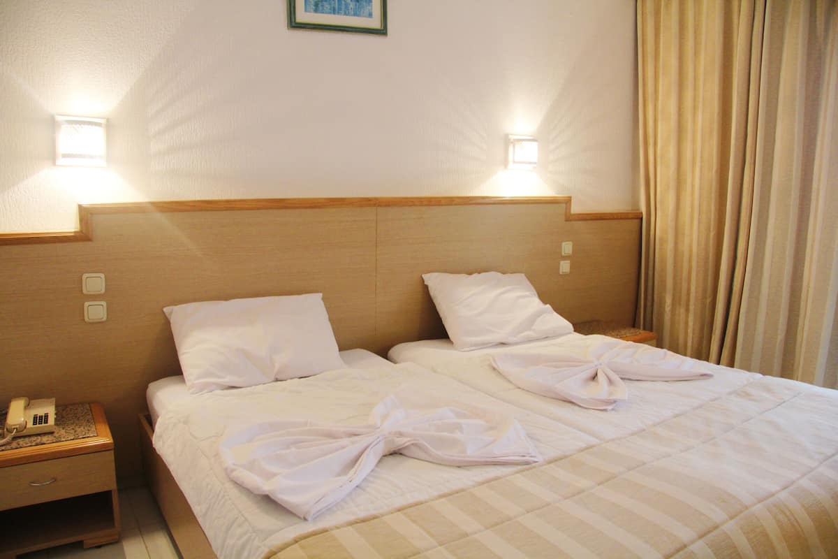 A hotel room with a double bed, two bedside tables, a telephone, and two wall-mounted lights.
