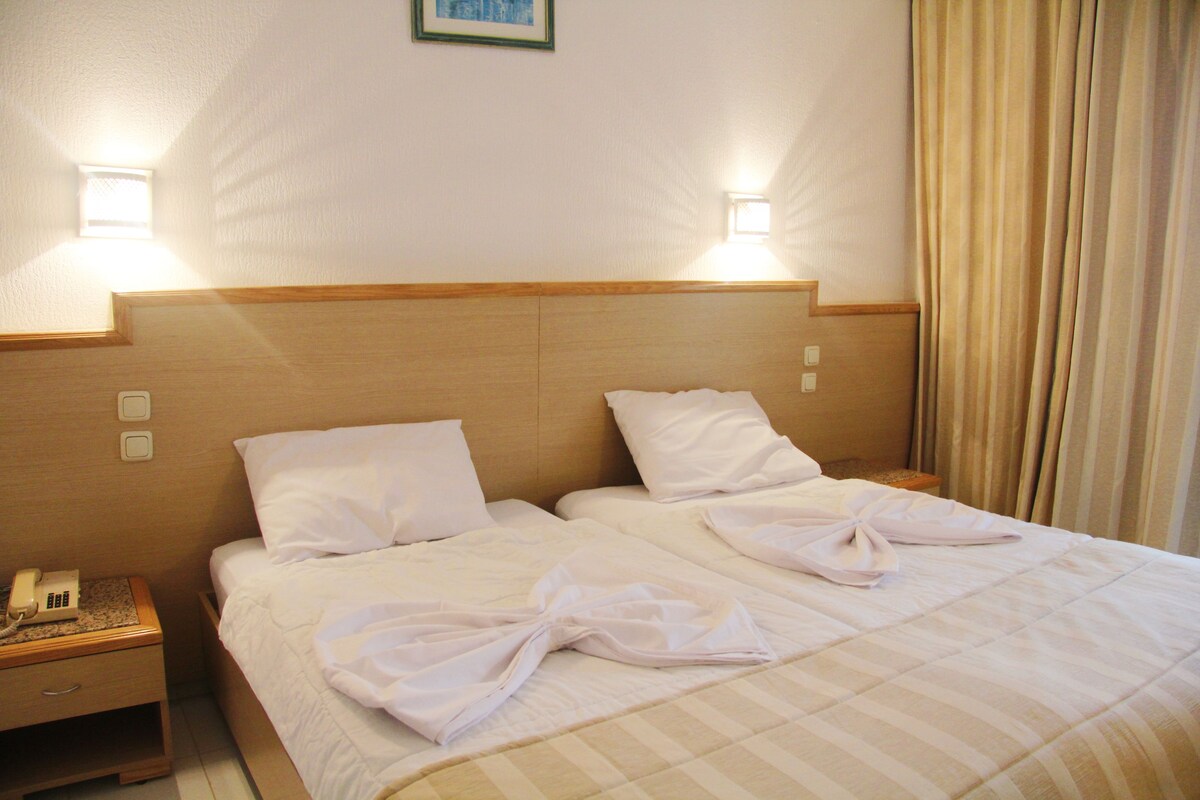 A hotel room with a double bed, two bedside tables, a telephone, and two wall-mounted lights.