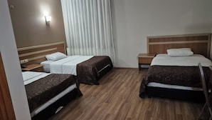 Une chambre d’hôtel avec deux lits, un plancher en bois, une table de chevet et une fenêtre avec des rideaux.