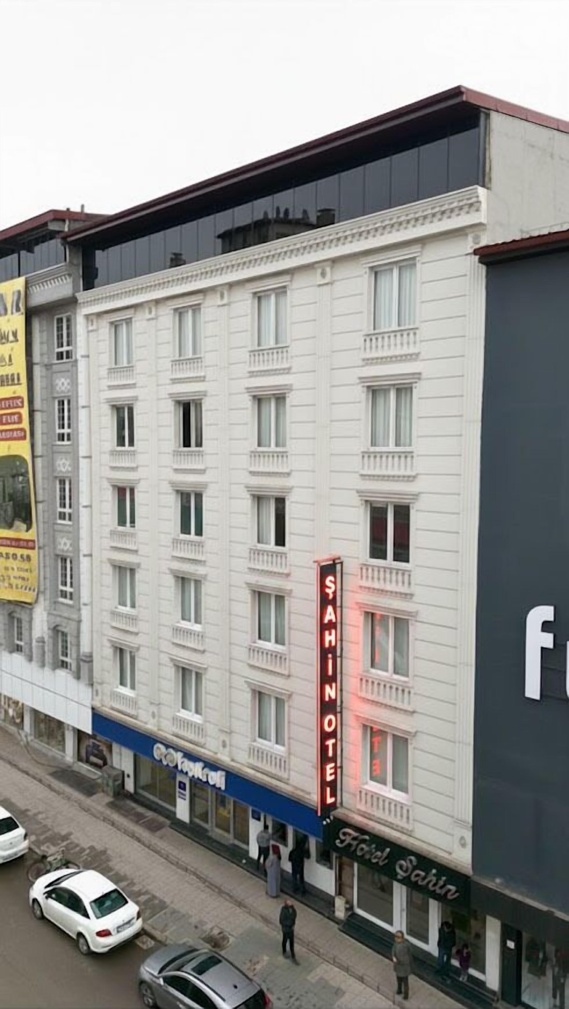 Un immeuble à plusieurs étages, dont la façade est ornée d’une enseigne bien visible indiquant « Hôtel Sahin ».