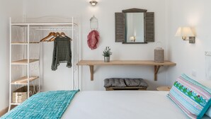 A bedroom with a bed, a wardrobe, a mirror, a shelf with a plant, and a bedside lamp. - Eco Soul Ericeira Guesthouse (Mafra)