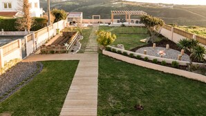 A well-maintained outdoor patio area with a wooden deck, a fire pit, and a pergola. - Eco Soul Ericeira Guesthouse (Mafra)