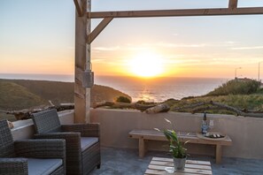 A balcony with wicker furniture, a wooden bench, and a table with a potted plant. - Eco Soul Ericeira Guesthouse (Mafra)