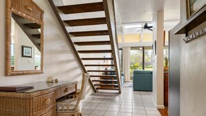 A modern interior with a staircase, wicker furniture, and a view to the outdoors. - Spacious Townhome with Golf Course Views (Kahuku)