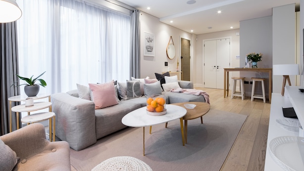 A modern living room with a grey sofa, a coffee table, and a dining area with stools. - VI Castle Lane (London)