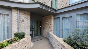 A modern building with a brick facade, large windows, and a glass door entrance. - VI Castle Lane (London)
