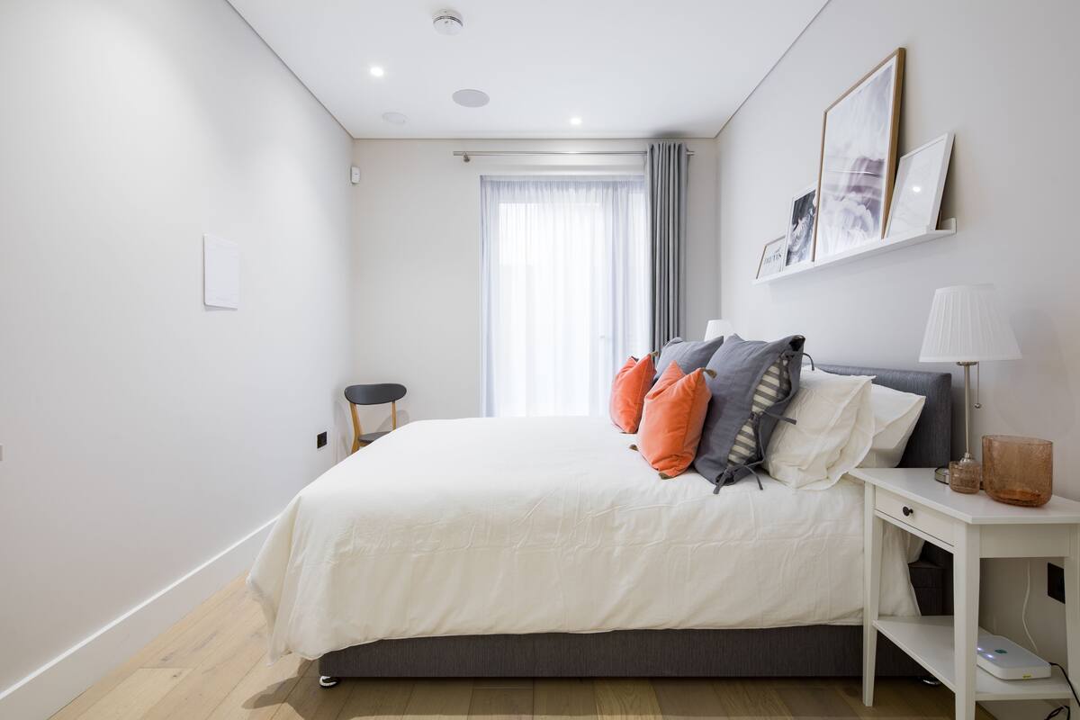 A modern bedroom with a bed, bedside table, and a window with curtains.