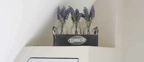 A welcome sign with vases of lavender on a wall.