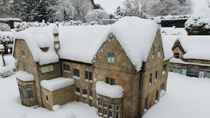 A historic building with multiple windows and a snow-covered roof, surrounded by snow. - The Old New Inn (Cheltenham)