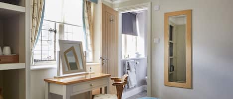 A bedroom with a wooden desk, chair, and a bed with a blue blanket.
