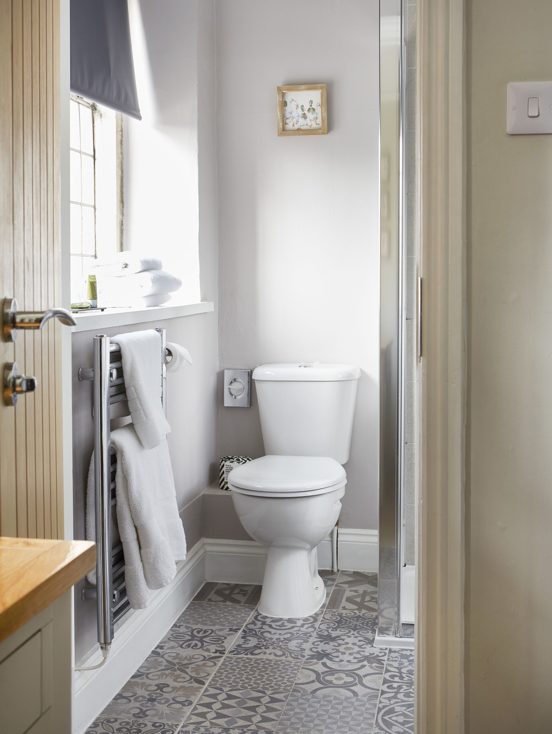 A bathroom with a toilet, a towel rack, a sink, and a shower area.