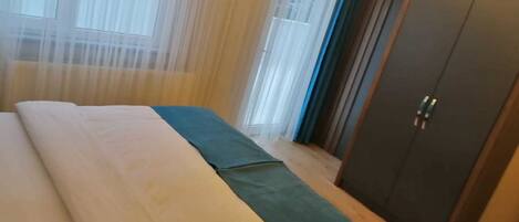 Un dormitorio con cama, armario y cortinas translúcidas.